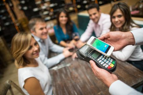 A group of people paying via their mobile phone