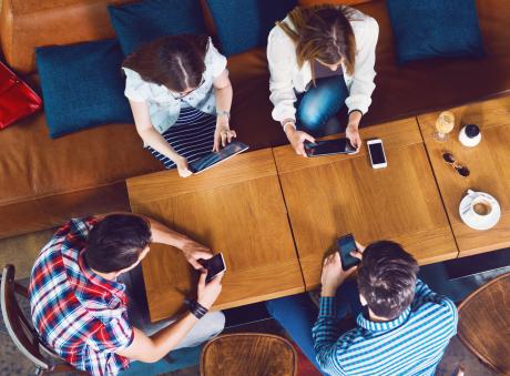 Group of friends using their mobile devices around a table